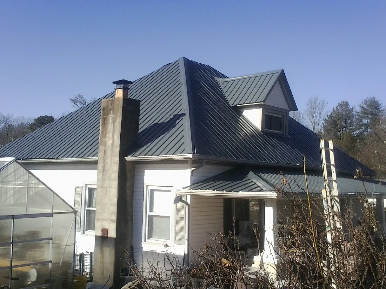 Dark blue standing seam metal roof on a white farmhouse with dormer — Slate & Tile Roof Repair by Roofing Brothers in Venango