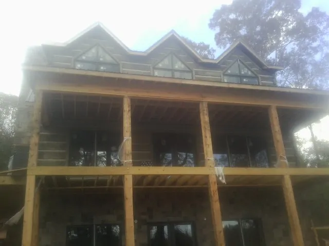 Dormers and porch framing on a large log home under construction — Roof Coating work by our crew in Venango