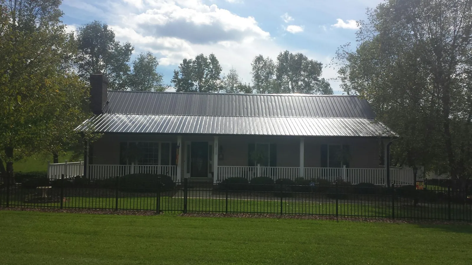 Gray metal roof on a brick ranch with a full width front porch — Gutter Guard Installation work by our crew in Venango